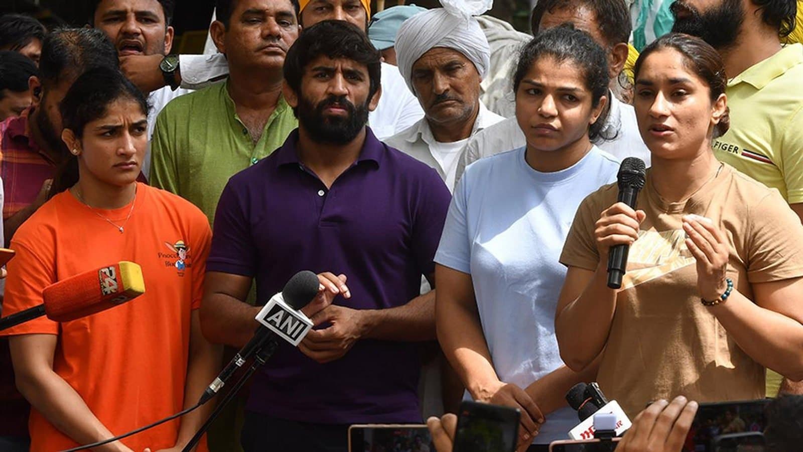 Wrestlers Vinesh Phogat, Bajrang Punia, Sakshi Malik and Sangeeta Phogat speaking to reporters at a protest, surrounded by microphones. File photograph from the 2023 protest march in New Delhi.