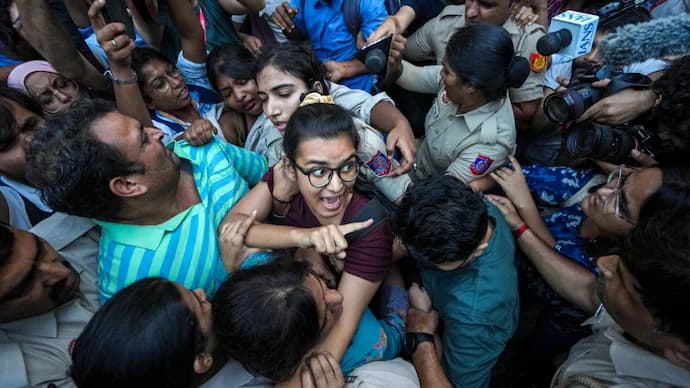 Police surround a woman protester amid a crowd during a scuffle at a Delhi protest