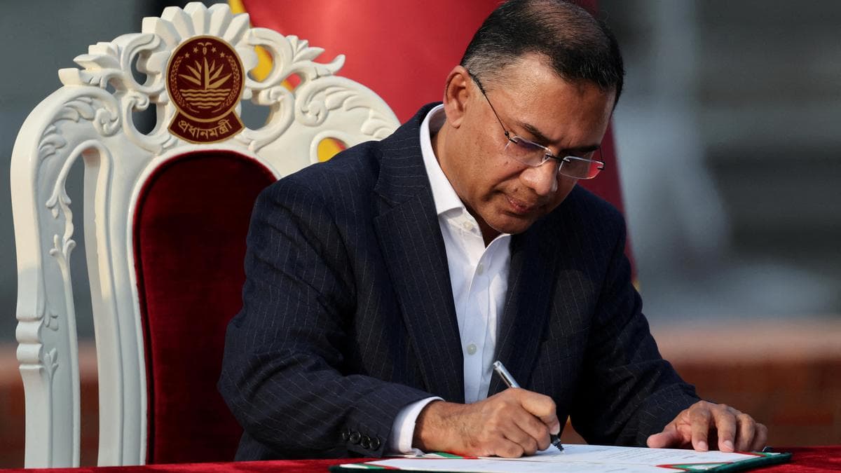 Bangladesh Prime Minister Tarique Rahman signs a document while seated in an ornate chair