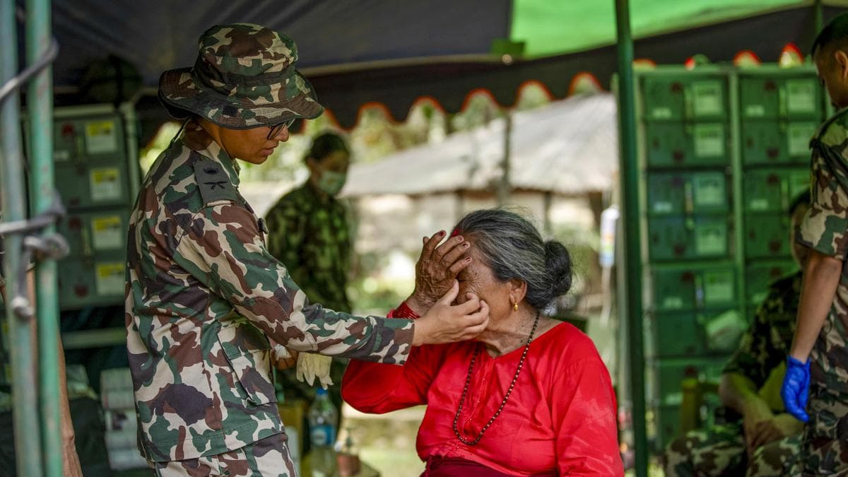 A Nepali Army soldier tends to an elderly woman at a relief camp after the floods