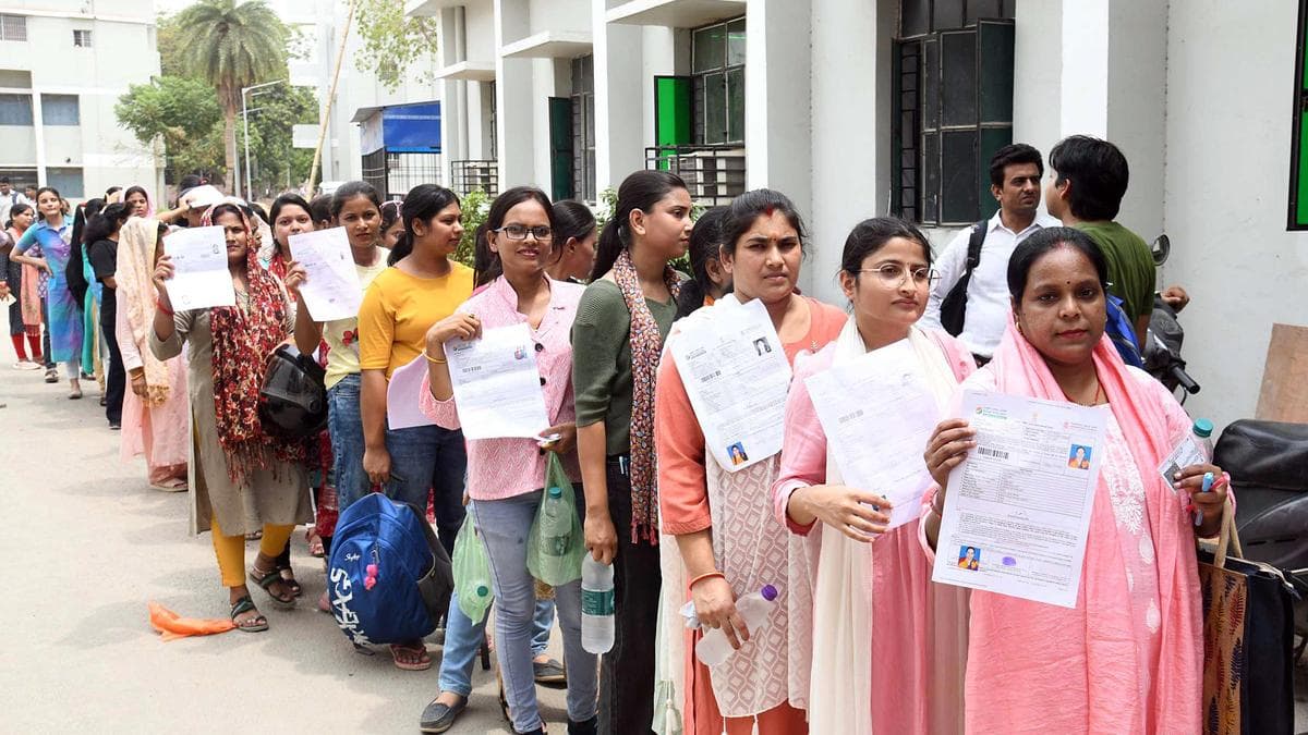 Candidates line up outside an exam centre holding their admit cards