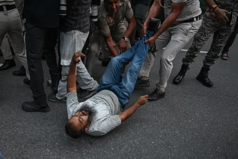 भारत में एक प्रदर्शन के दौरान पुलिसकर्मी एक प्रदर्शनकारी को सड़क पर घसीटते हुए
