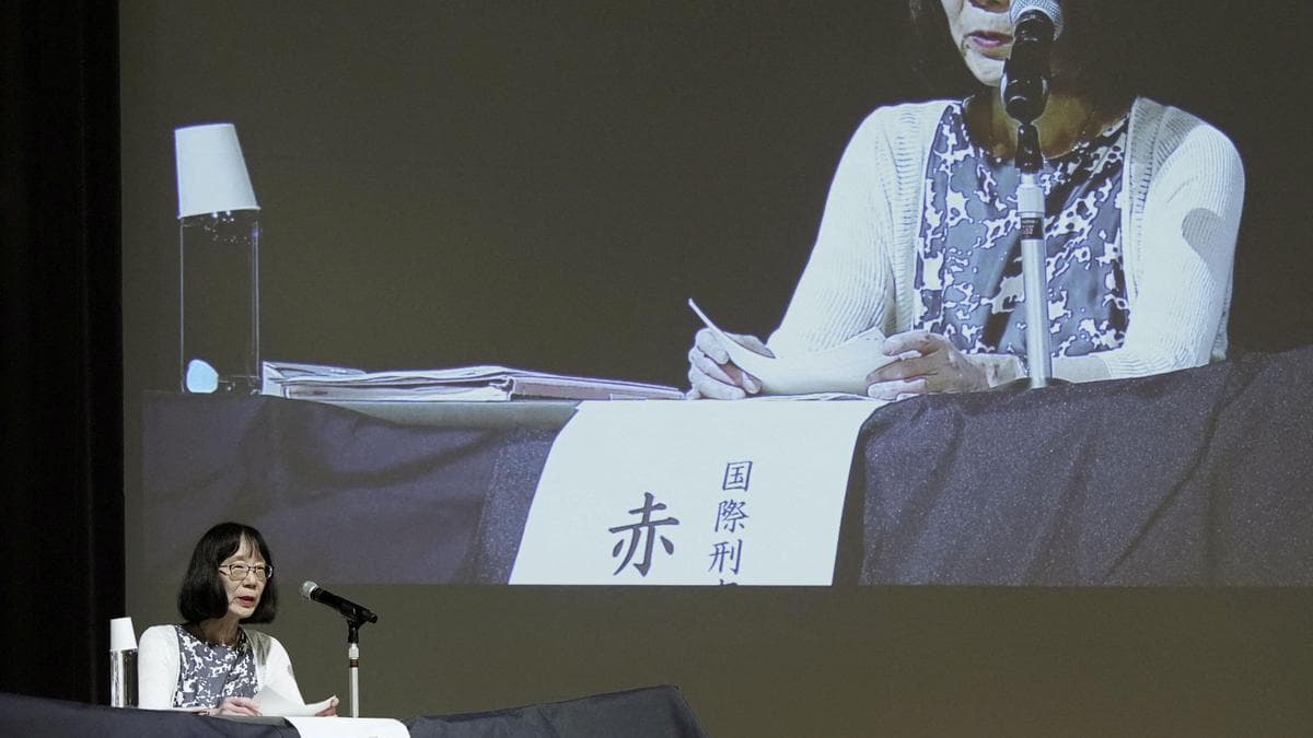 ICC President Tomoko Akane speaking at a press briefing displayed on a large screen